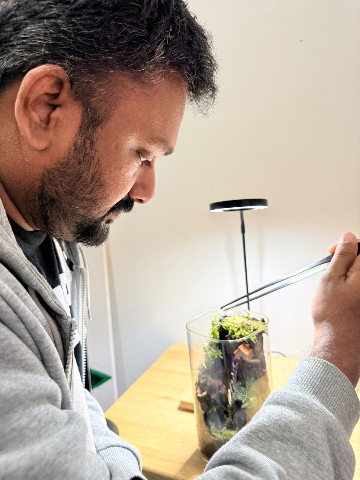 Jyothish, founder of Terra World, placing moss inside a glass terrarium with long tweezers
